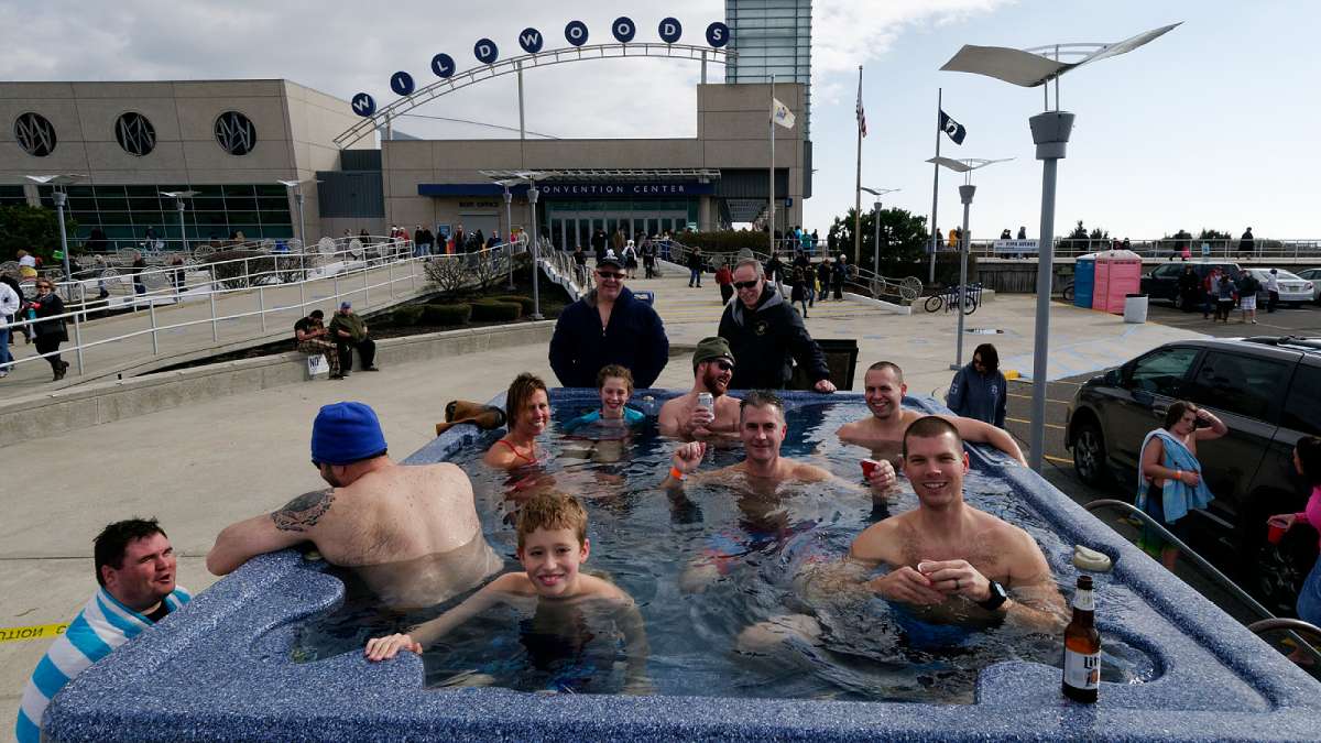 After a dip in the 48 degree ocean police officers with families warm up in a hot tub, set up by Scott Jarvis (not pictured) outside the Convention Center. (Bastiaan Slabbers/for NewsWorks)