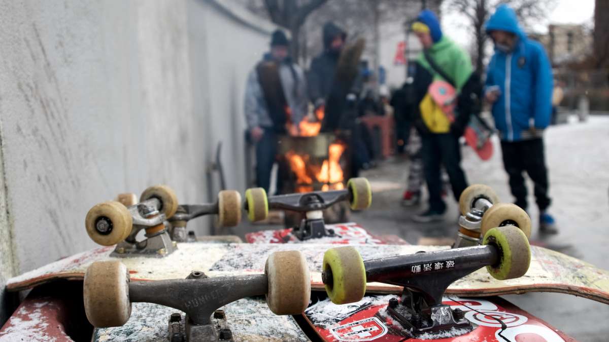 Boards rest on one of the pink planters as skaters warm by a fire pit.