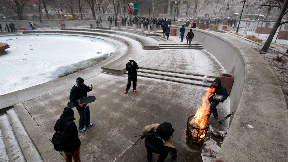 A trash can is turned into a fire pit to help warm the skaters.