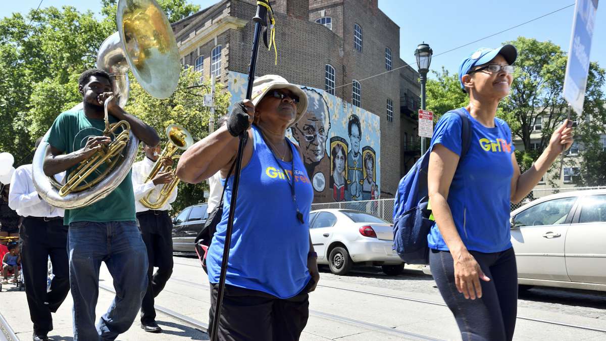 The parade marches past the Women of Germantow mural on the side of the Germantown YWCA as it heads towards the Juneteenth Festival, near Johnson House.