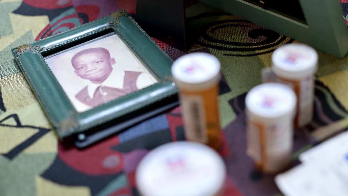 Surrounded by medicine canisters, a photo of Kenyada Jones as a young boy lies on the dinner table at his mother's house.