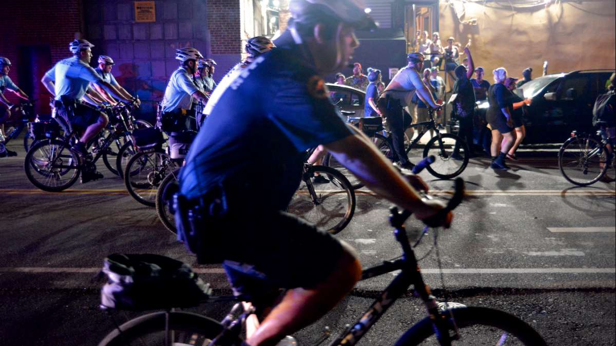 The Police Department's Bike Patrol Unit and a cruiser trail the protesters from a distance, while a helicopter follows overhead.