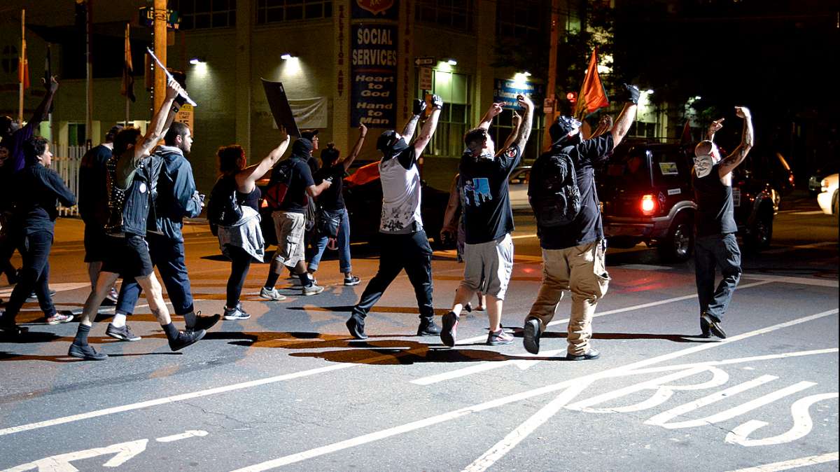 Protesters, including at least four unidentified British men (seen on the right) gesture into the spotlight from the PPD helicopter.