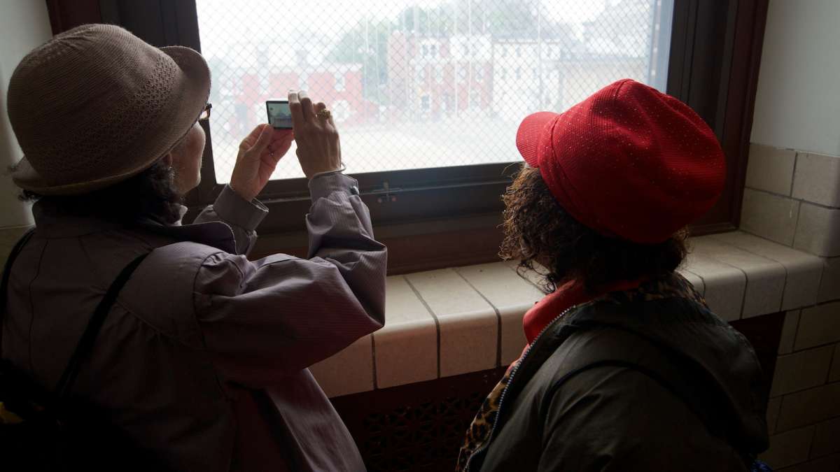 Visitors capture an image of the neighborhood as seen from inside the shuttered Fulton Elementary School on East Haines Street. (Bas Slabbers/for NewsWorks)