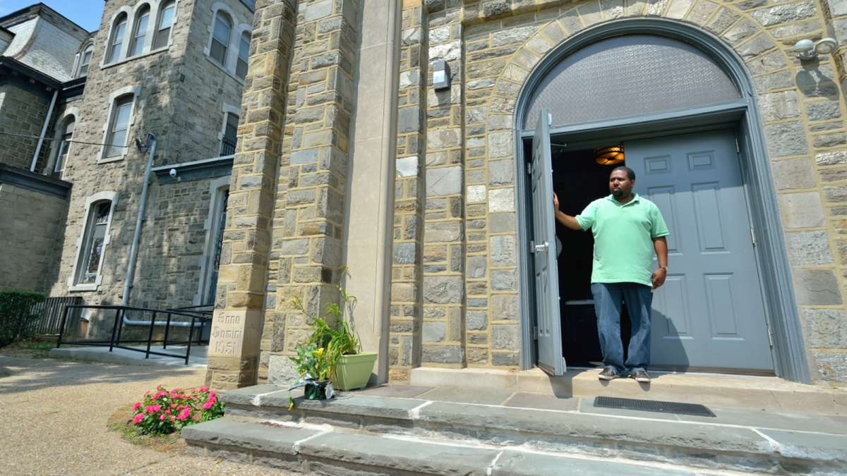 Karim Rogers holds open the door of a former church that now houses a performing-arts center on the Germantown Settlement campus, located in the 4800 block of Germantown Ave. (Bas Slabbers/for NewsWorks)