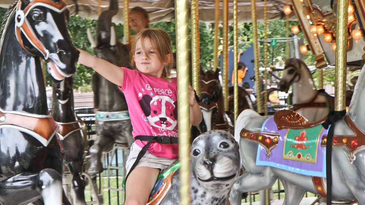  Kacey Aneser and her sister Kelly wave to their mom from the carousel at Franklin Square. (Kimberly Paynter/WHYY) 