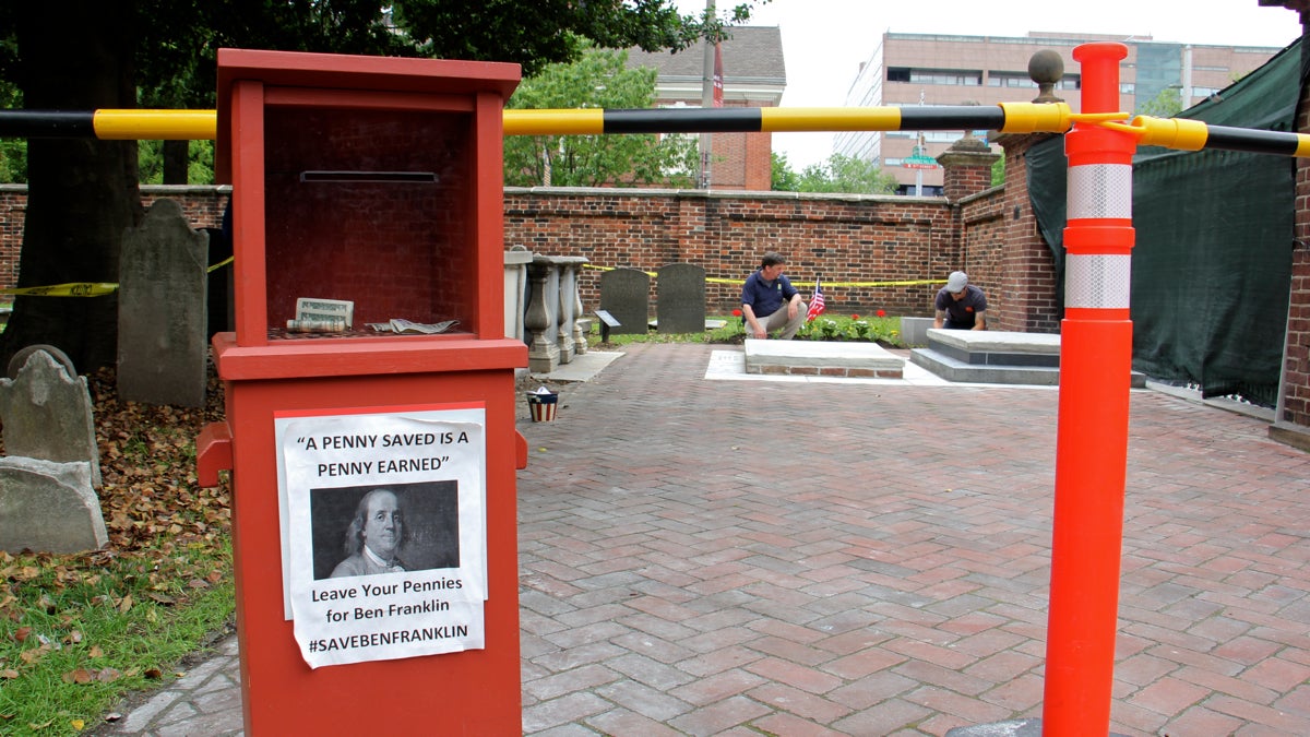  John Hopkins (center), burial ground and tourism manager for Christ Church, watches as a workman puts the final touches Ben Franklin's restored grave. (Emma Lee/WHYY) 