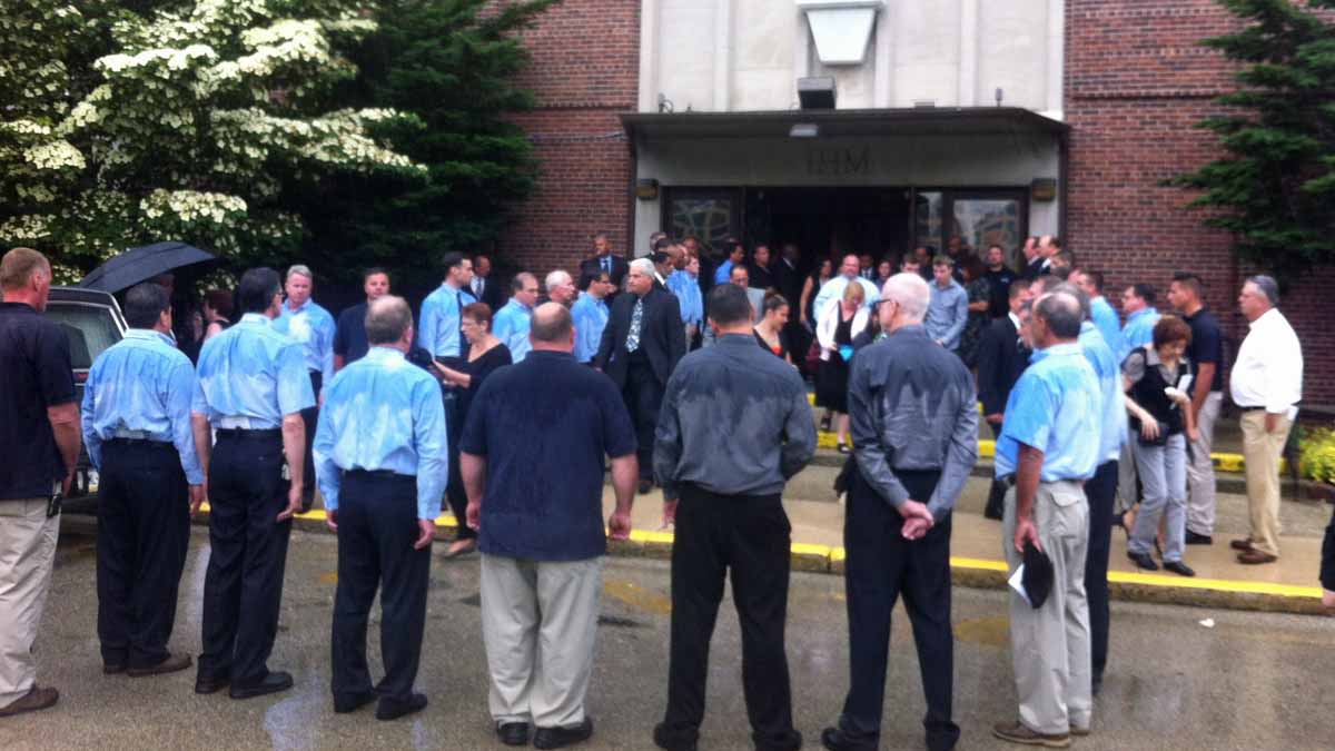  After Wagenhoffer's church service, a group of L&I inspectors and staffers in matching blue shirts led the casket out of the church in a downpour. (Amy Z. Quinn/ for NewsWorks) 