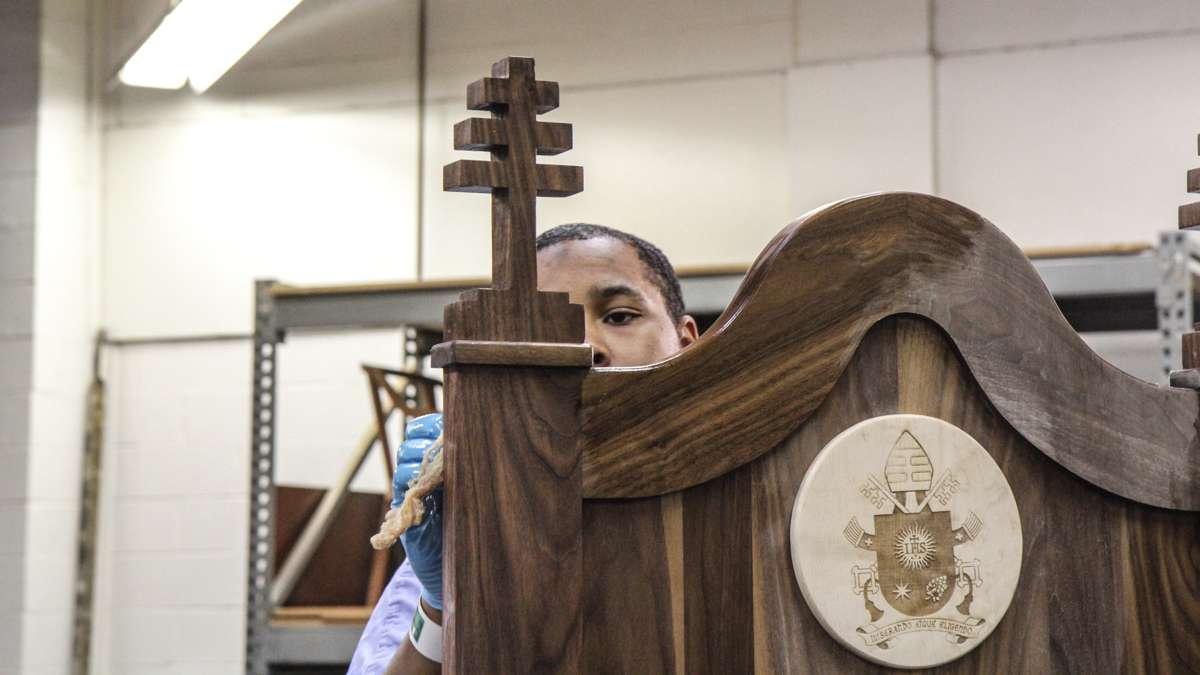 Inmate Hakim Burke varnishes the chair made for Pope Francis at Philadelphia Industrial Correctional Center. (Kimberly Paynter/WHYY)
