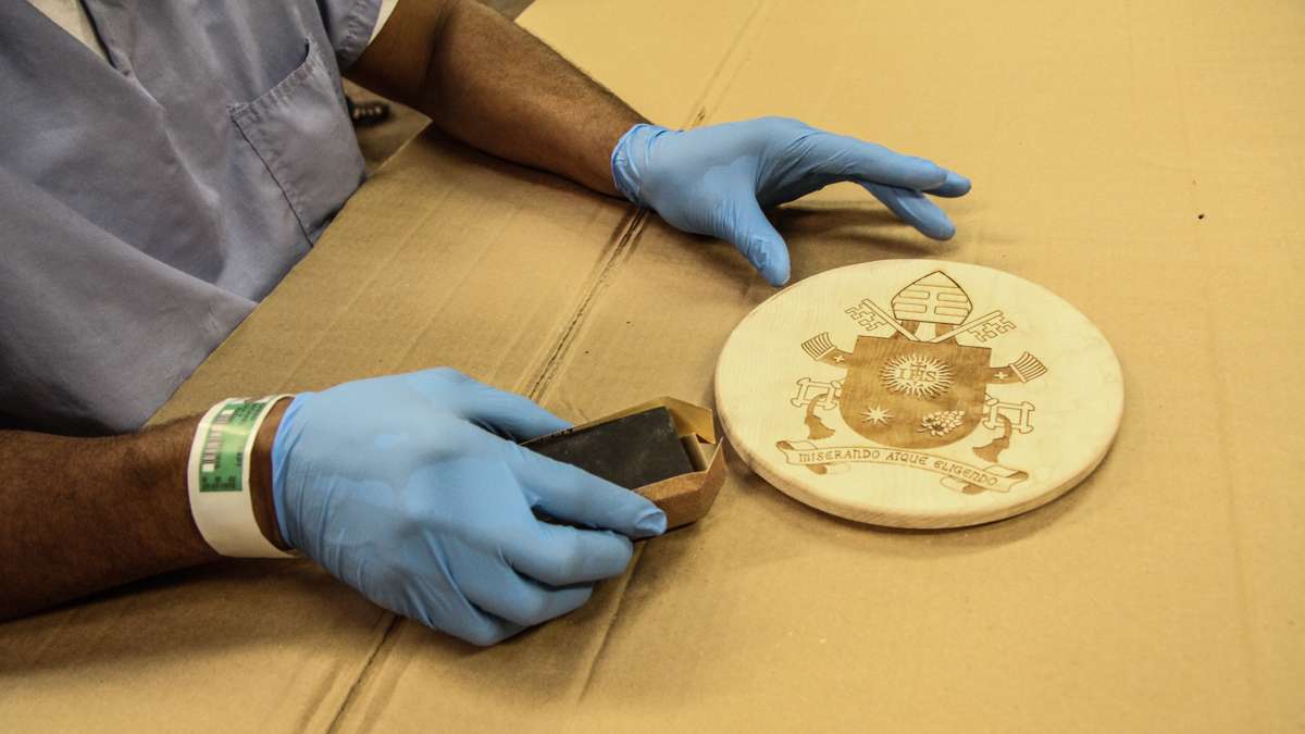 Michael Green sands the seal to be placed on the pope's chair. (Kimberly Paynter/WHYY)