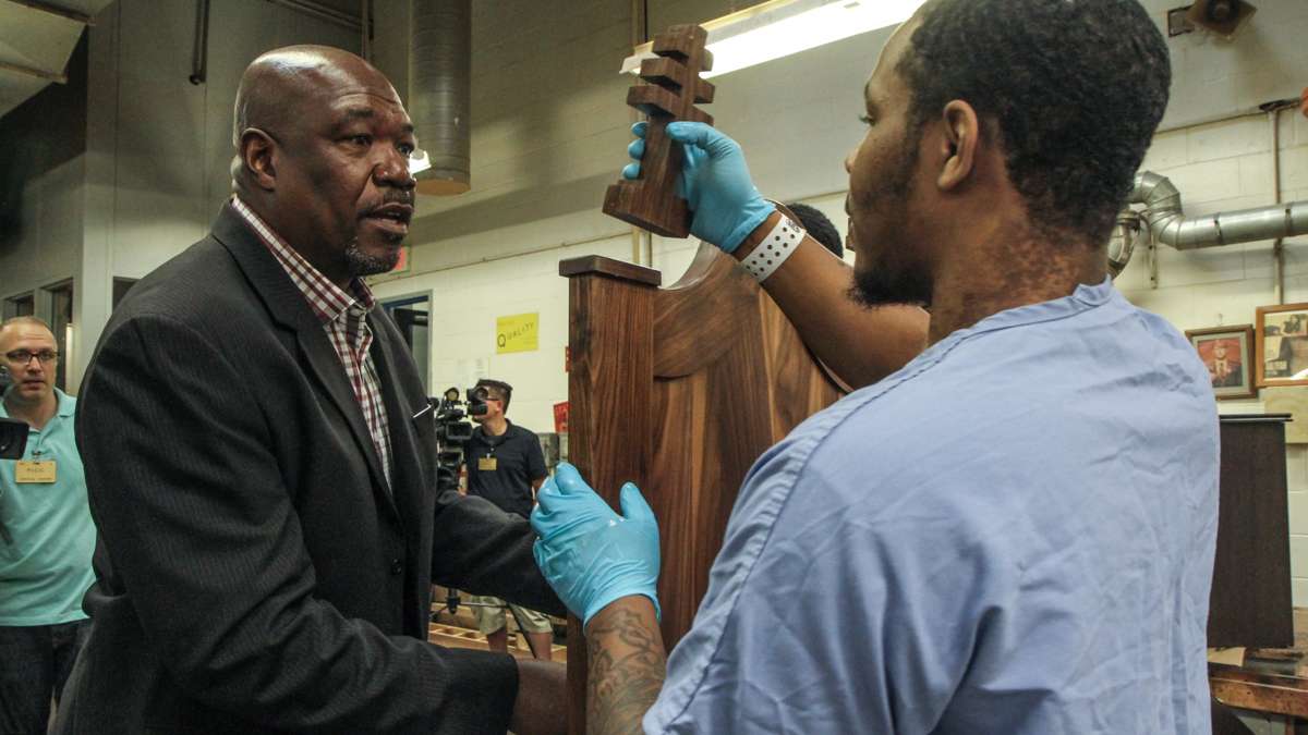 Chair Designer Anthony Newman instructs an inmate on where to place one of the chair's crosses. (Kimberly Paynter/WHYY)