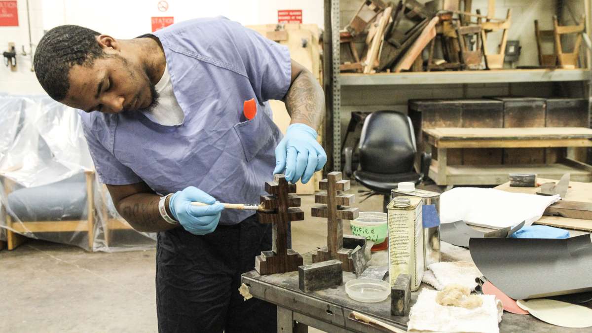 Inmate Hakim Burke varnishes the crosses for Pope Francis' chair at Philadelphia Industrial Correction Center. (Kimberly Paynter/WHYY)