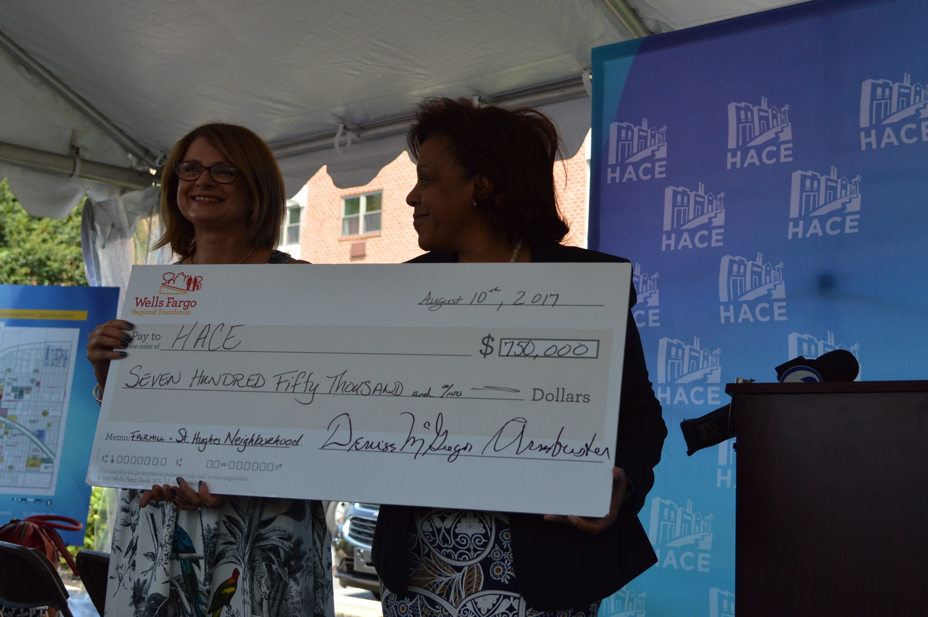  Denise McGregor-Armbrister (right) of the Wells Fargo Regional Foundation presents a check to HACE President Maria Gonzalez for use in redeveloping the Fairhill-St. Hugh neighborhood.   (Tom MacDonald/WHYY) 