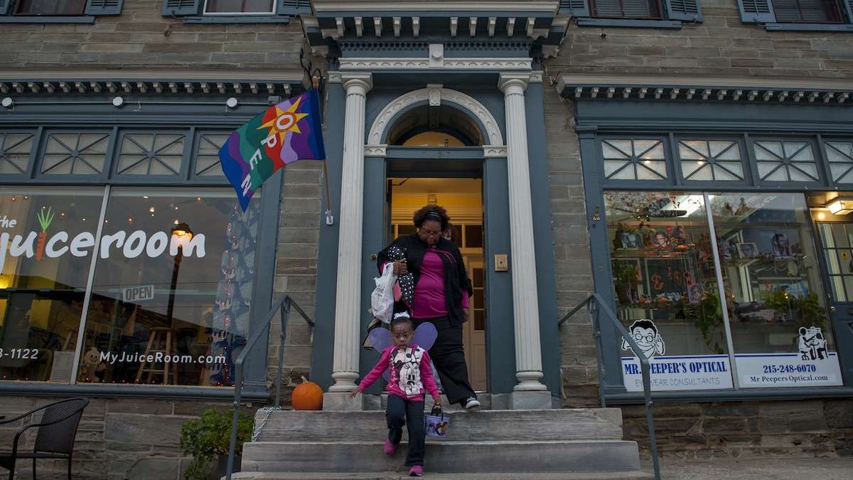 Ruth Stroman, of Mt. Airy, and her daughter Madison, 3, leave The Juiceroom after trick-or-treating there on Halloween evening. (Tracie Van Auken/for NewsWorks)