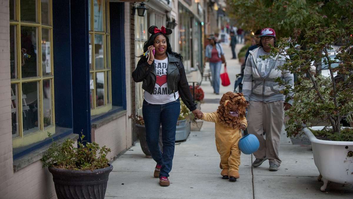 Tyrena Jackson (left), of Mt. Airy, takes her son Zaiking Jackson, 2, trick-or-treating at the shops on Germantown Avenue with Rashea Martin (right) on Halloween night. (Tracie Van Auken/for NewsWorks)