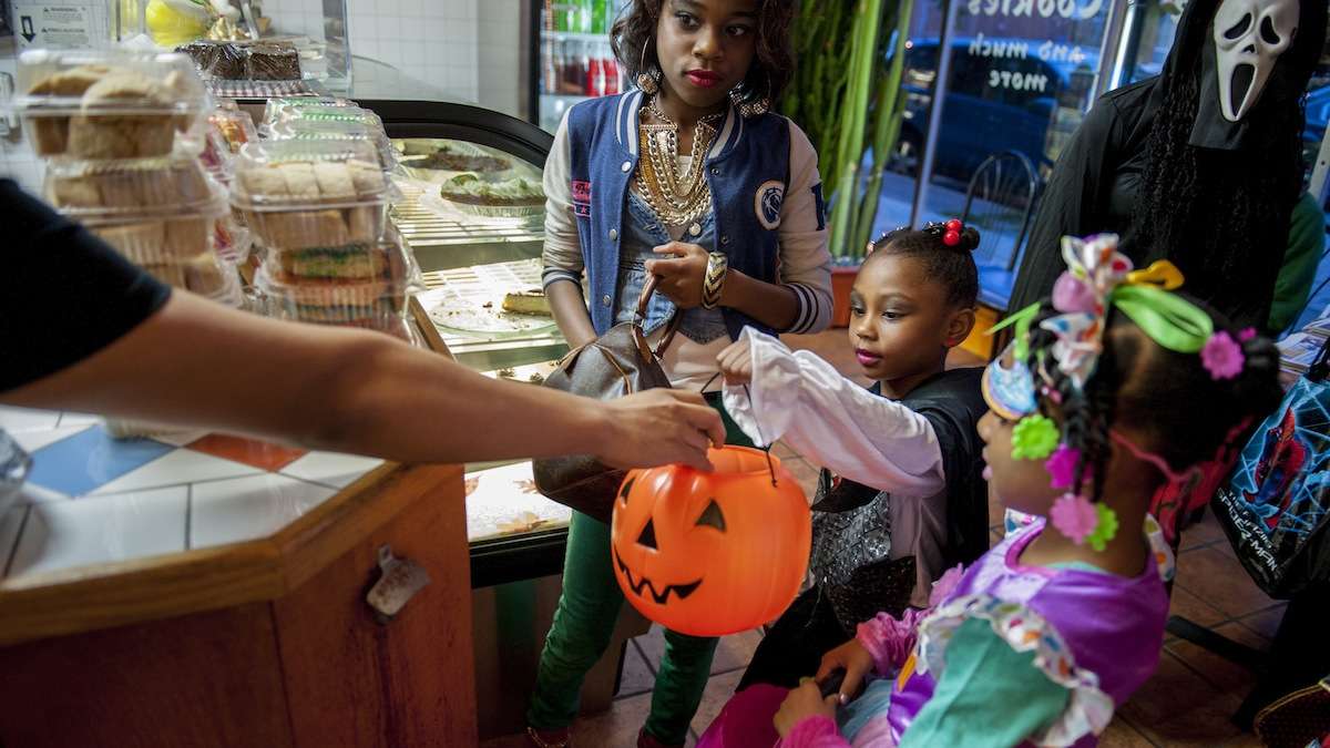 Saige Frazier (center), 5, of Mt. Airy, gets candy at Mi Puebla Mexican Food Restaurant on Germantown Avenue Halloween night. With her are her sister, Amanda Frazier (left), 10, and Kya Conyers (right), 5. (Tracie Van Auken/for NewsWorks)