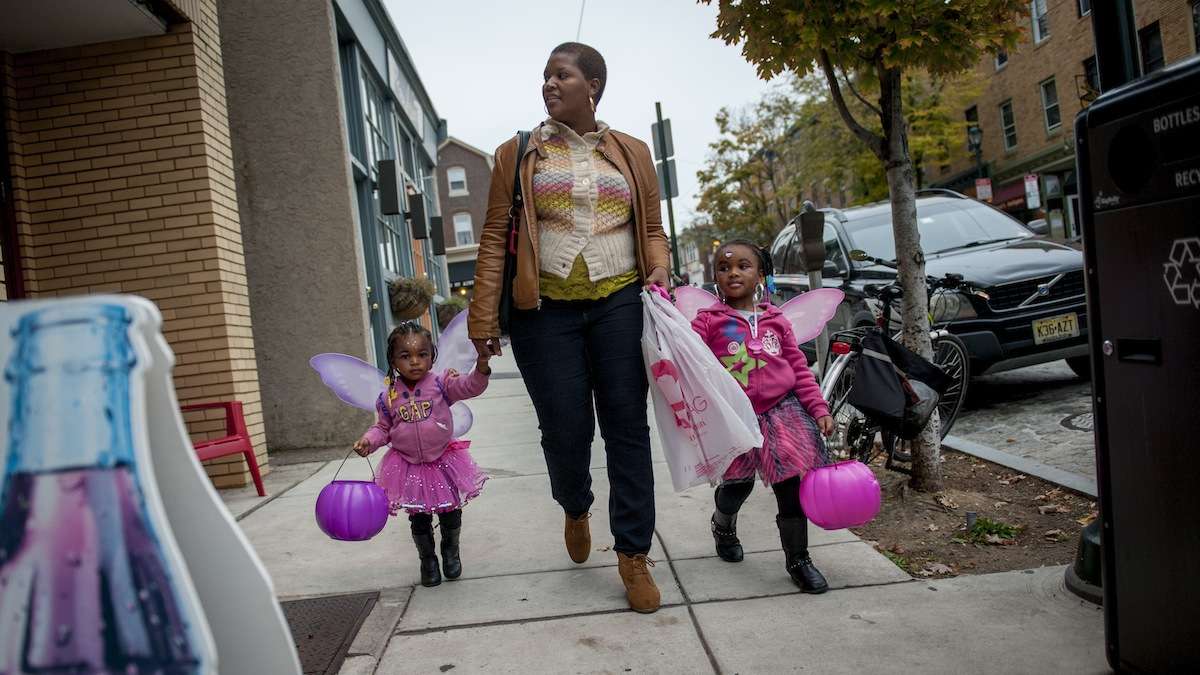 Sharrell Littles, of Mt. Airy, walks with her daughters, LaShae (left), 2, and LaShari, 4, while trick-or-treating on Germantown Avenue Halloween night in 2013. (Tracie Van Auken for WHYY)