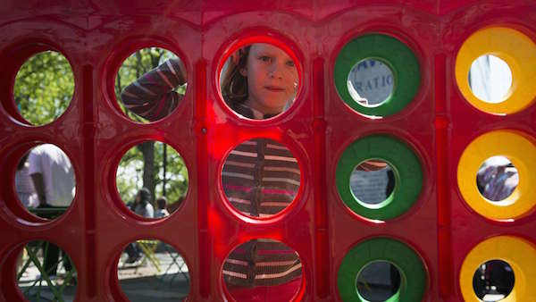 Alma Nikaé stares through the holes of a giant connect four game during opening weekend of the Spruce Street Harbor Park.