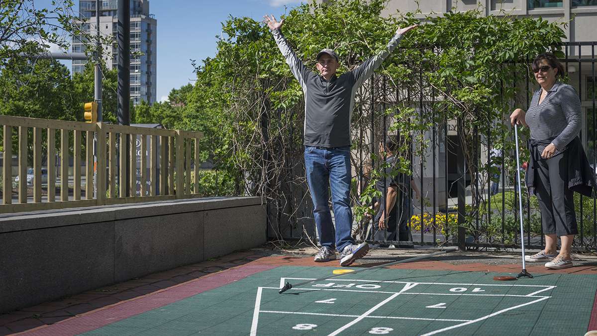 Lou Troilo celebrates a shuffleboard victory over family members at the opening weekend of the Spruce Street Harbor Park.