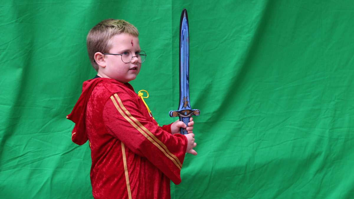 Jamison Walsh, 6 poses in front of the green screen with his magic sword (Natavan Werbock/for NewsWorks)