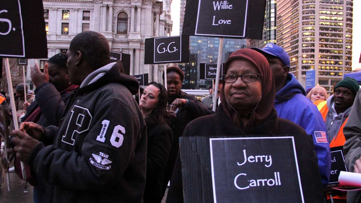 Charlene Wells carries a sign for Jerry Carroll, a man she remembered would ask for change for coffee. She heard he died on the street. (Emma Lee/for NewsWorks)