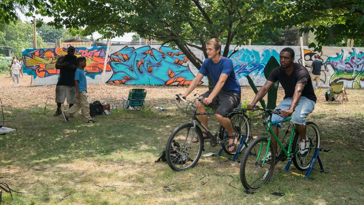 Jesse Phillips (left) and Cool Cceez ride stationary bikes which power a sound system at the 4th annual Hoodstock Festival at Life Do Grow Farm