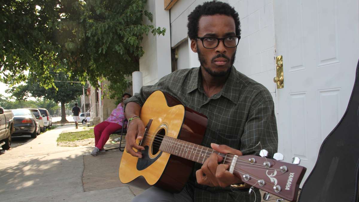 Calvin Okunoye strums the gaucho song he will play for his rider during the horse tuning. (Emma Lee/WHYY)