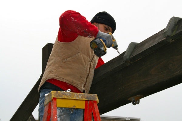 <p><p>A volunteer stands atop a ladder while drilling in some bolts on Henry H. Houston's playground swing set. (Lane Blackmer/for NewsWorks)</p></p>
