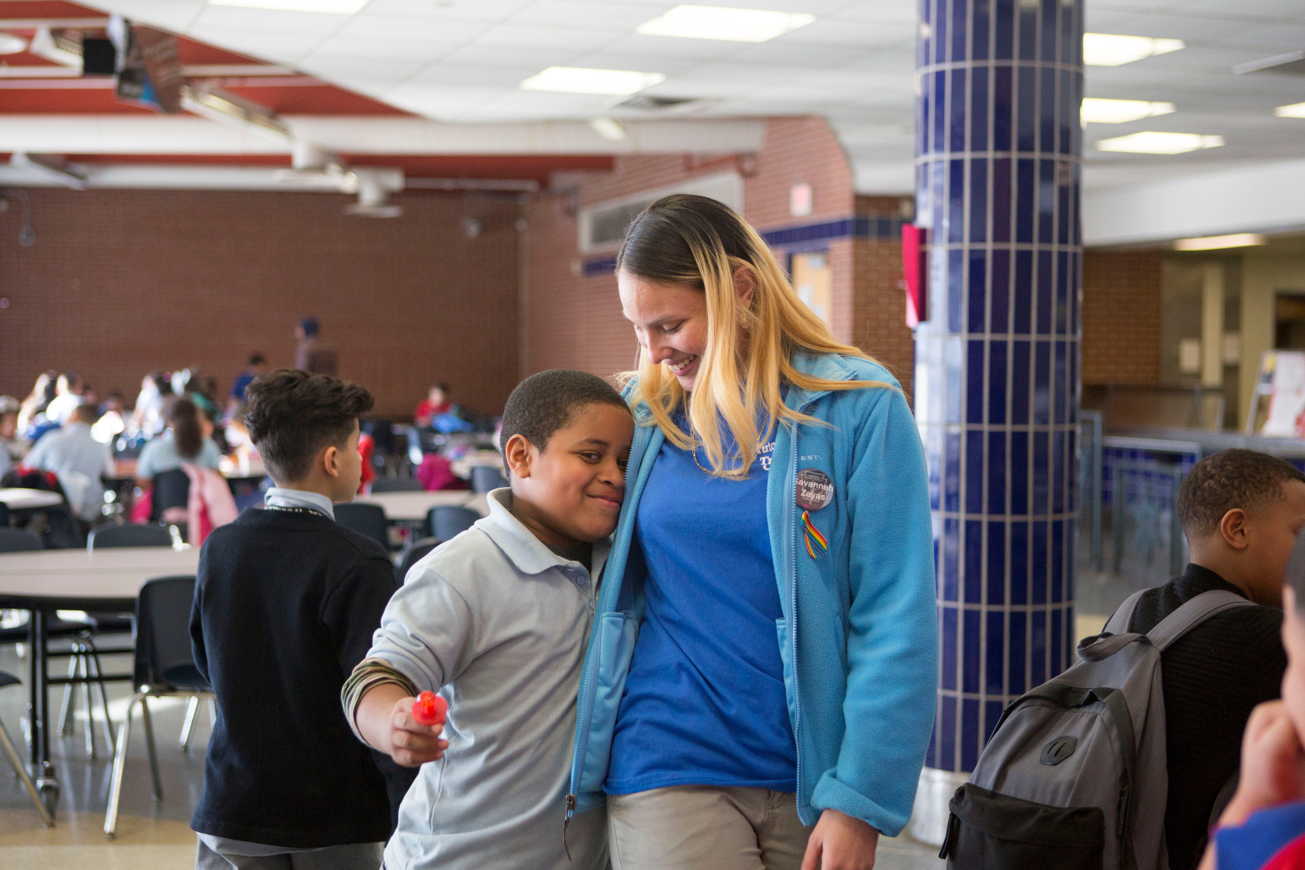 </b> Savannah, in her role as a teen leader in The Providence Center’s after school program, hugs an elementary school student. (Jessica Kourkounis/For Keystone Crossroads) 
