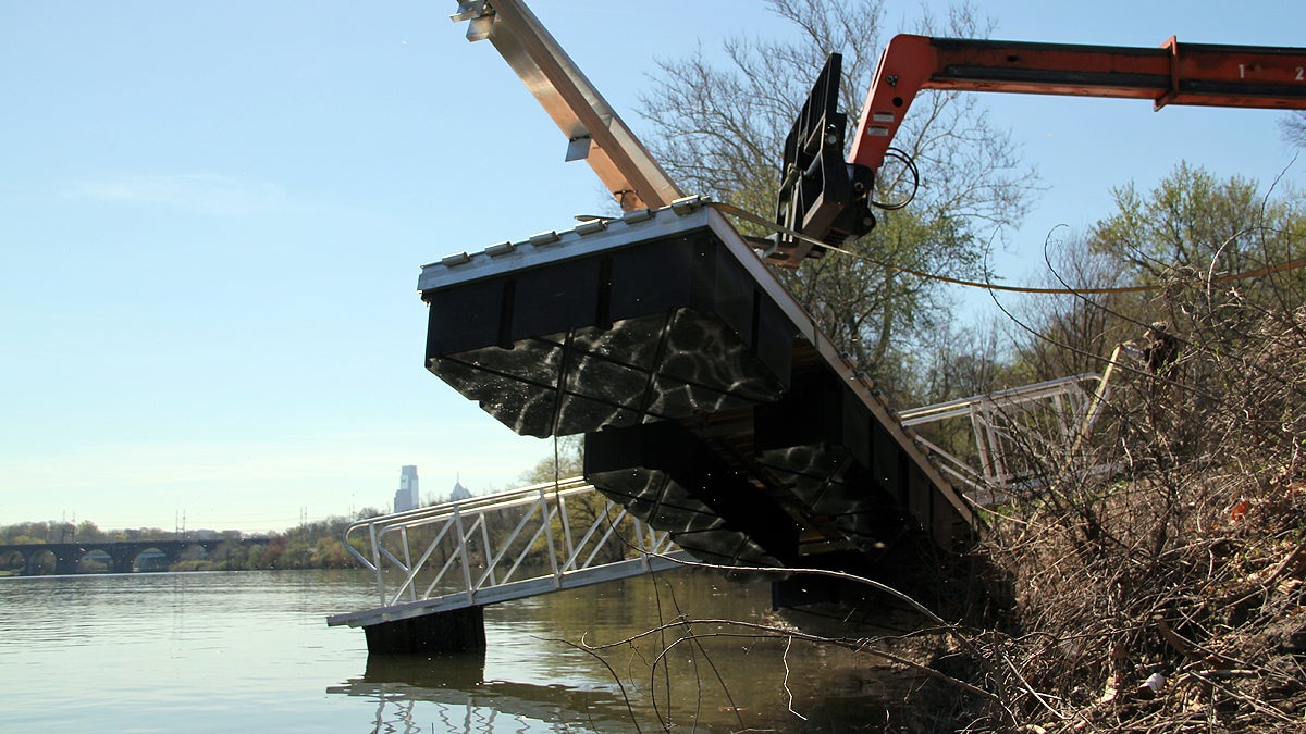  A prefabricated section of the dragon boat dock is lowered into the Schuykill River. (Emma Lee/for NewsWorks) 