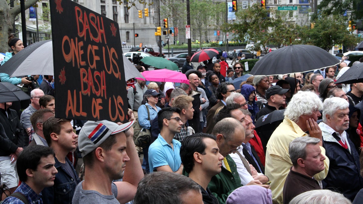 Standing in the rain, the somber crowd listens to a series of speakers, many of whom urged hate crime legislation that would include attacks motivated by sexual orientation. (Emma Lee/WHYY)