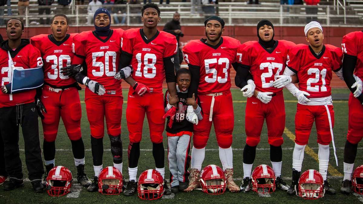 The Imhotep Panthers lock arms before taking the field in Saturday's PIAA AAA City Championship game against Archbishop Wood. (Brad Larrison/for NewsWorks)