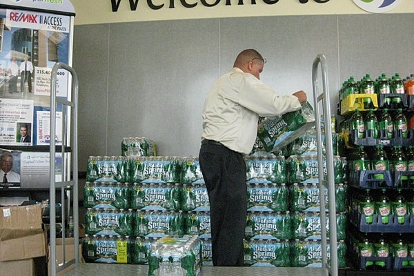 A Superfresh employee replenishes depleted stocks of bottled water at a store in the Northern Liberties. (Peter Crimmins/For NewsWorks)