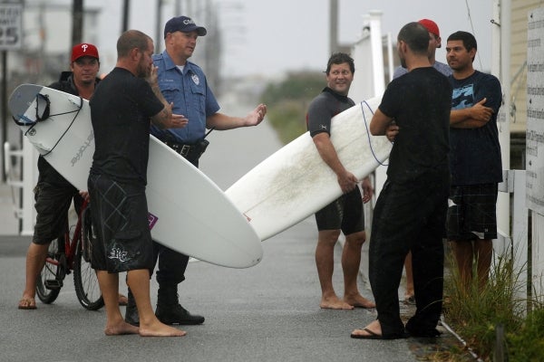 A Cape May police officer, second from left, talks with a group of surfers on the boardwalk early Saturday, Aug. 27, 2011, in Cape May, N.J. (AP Photo/Mel Evans)