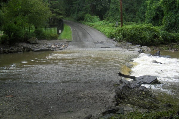 Mill Creek spills over Righters Mill Road Sunday in Gladwyne. (Jennifer Lynn/For NewsWorks)