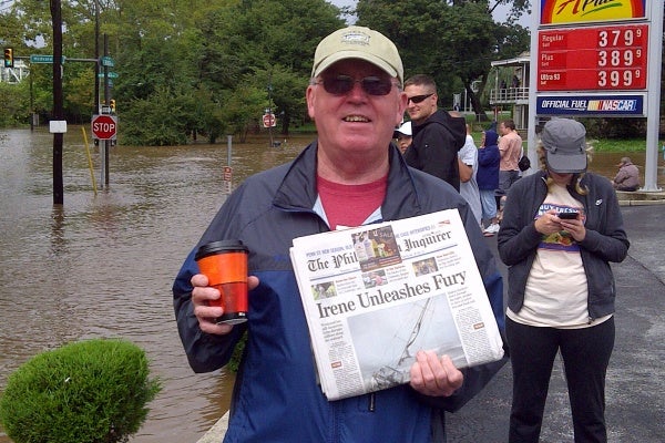 Sam Malloy, of East Falls, holds up a newspaper about Hurricane Irene. (Brian Hickey/For NewsWorks)