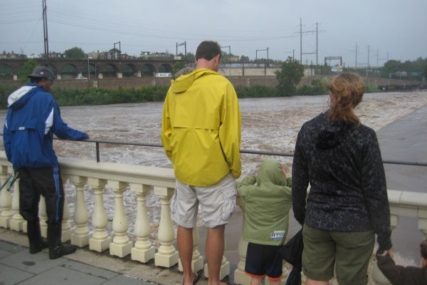 A few people stop to take a look at the water levels from the pier at Fairmount Water Works. (Maiken Scott/For NewsWorks)