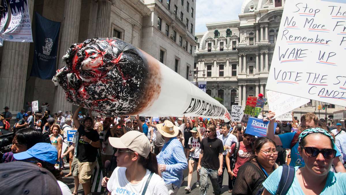 Marijuana legalization demonstrators carry a 50 foot inflatable joint down South Broad Street mingling with Bernie Sanders supporters on their way to FDR Park during the Democratic National Convention in 2016. (Brad Larrison for WHYY)