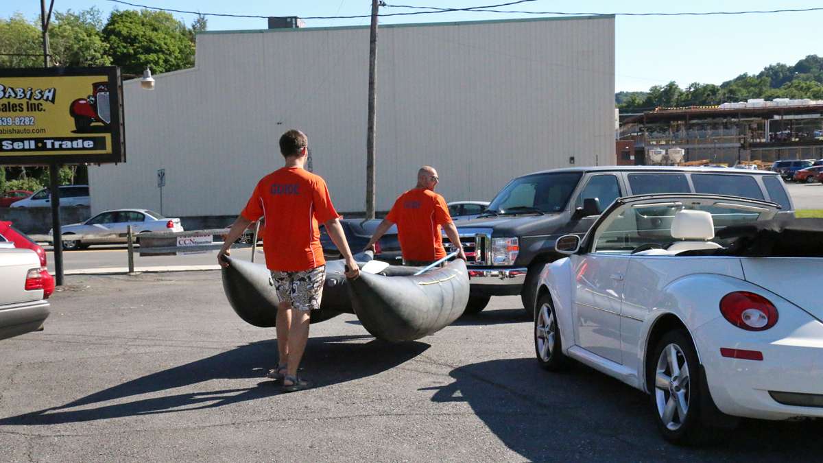 Bob Bridges and Matthew Wehner of Coal Tubin’ load the shredder into a van at the used car dealership.  (Lindsay Lazarski/WHYY)