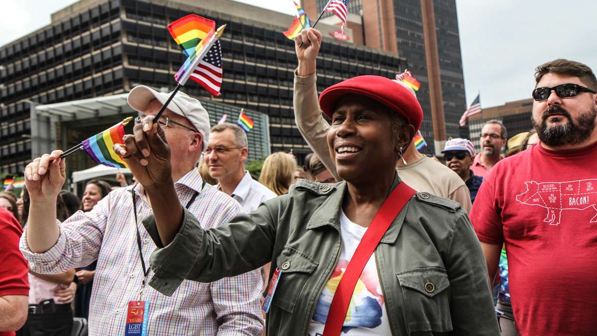 Kati 'Jazzy' Gray-Sadler waves flags during Philadelphia's 4th of July celebration of the 50th anniversary of the LGBT civil rights movement. (Kimberly Paynter/WHYY)