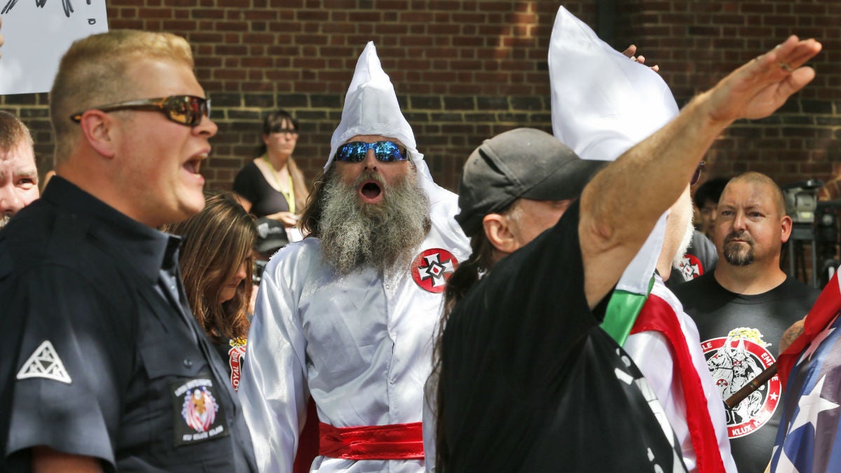  Members of the KKK are escorted by police past a large group of protesters during a KKK rally Saturday, July 8, 2017, in Charlottesville, Va. (AP Photo/Steve Helber) 