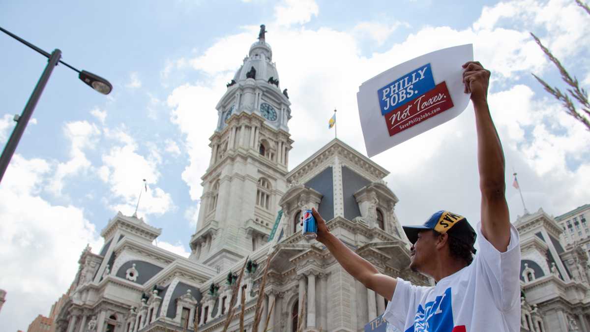  A beverage industry supporter protests the sweetened beverage tax outside of Philadelphia's City Hall. A panel of Commonwealth Court judges will hear arguments over the levy Wednesday in Pittsburgh. (NewsWorks file photo) 