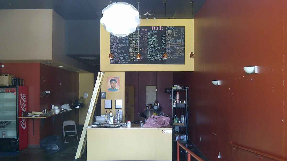  The view inside the now-shuttered Wired Beans Cafe at Germantown's Chelten Plaza. A painting of owner Robert Wheeler sits to the right of the ladder. (Brian Hickey/WHYY) 