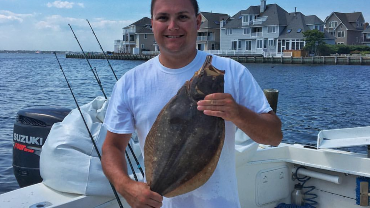  Angler Andrew Pero holds up a summer flounder after arriving back at port in South Seaside Park in August 2016. 