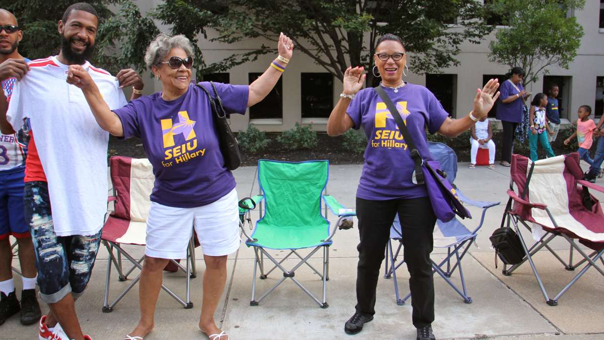 Parade watchers get up and dance to the sound of drums as a drill team passes on Columbus Boulevard. (Emma Lee/WHYY)