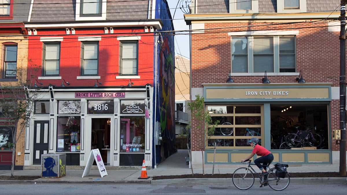  A cyclists rides past restaurants and boutique shops on Butler Street in the Lawrenceville neighborhood of Pittsburgh, Pa. (Lindsay Lazarski/WHYY) 
