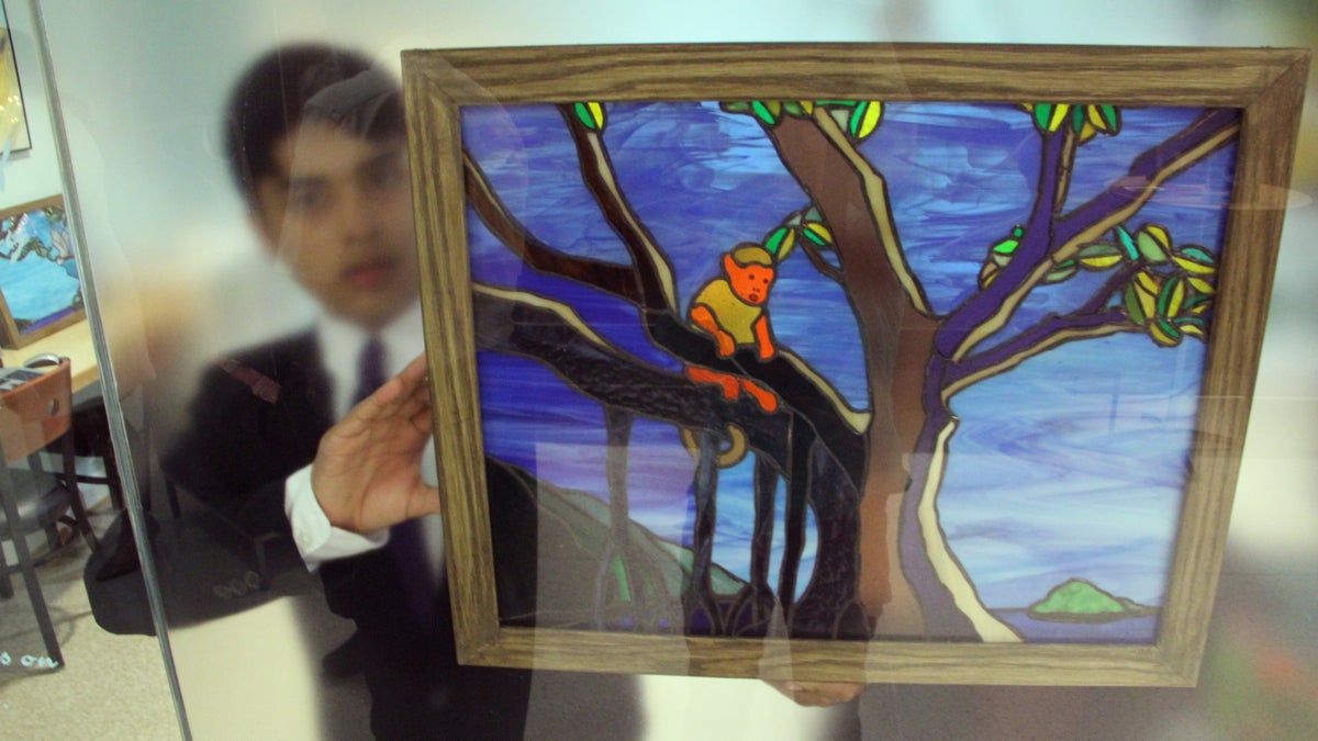 David Learner-Wagner holds one of his stained-glass panels against the frosted glass of the Children's Room at Penn Hospice at Rittenhouse. (Emma Lee/WHYY)