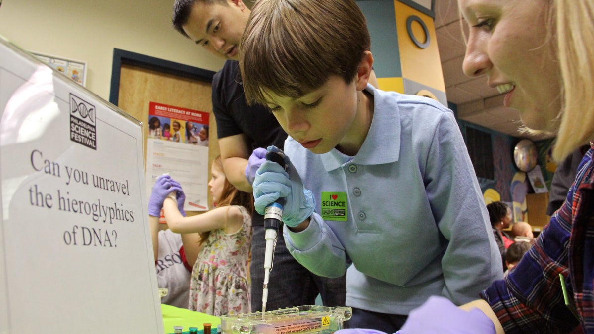 With the help of volunteer Jessica Perino, Jason Sagle, 9, goes through the process of testing a DNA sample to solve a crime. (Emma Lee/WHYY)