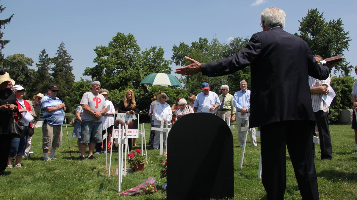 The Rev. William Terrence Devlin prays over a gravesite where his group believes the remains of fetuses found in Dr. Kermit Gosnell's abortion clinic were buried. (Emma Lee/WHYY