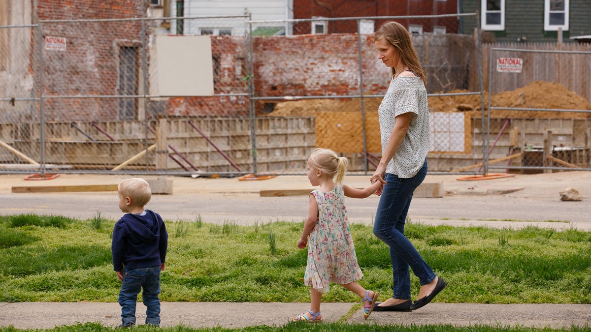 Jana Curtis and two of her children walk past one of many construction sites in their river ward neighborhood. Three-year-old Nolyn Pace, center, was poisoned by lead in the soil in their backyard. (Jessica Griffin/Philadelphia Media Network) 